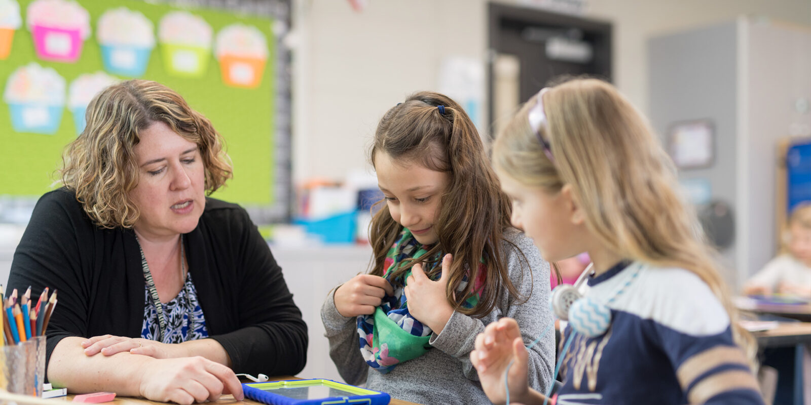 Education-maed-1 Female professor teaching two young girls in a classroom
