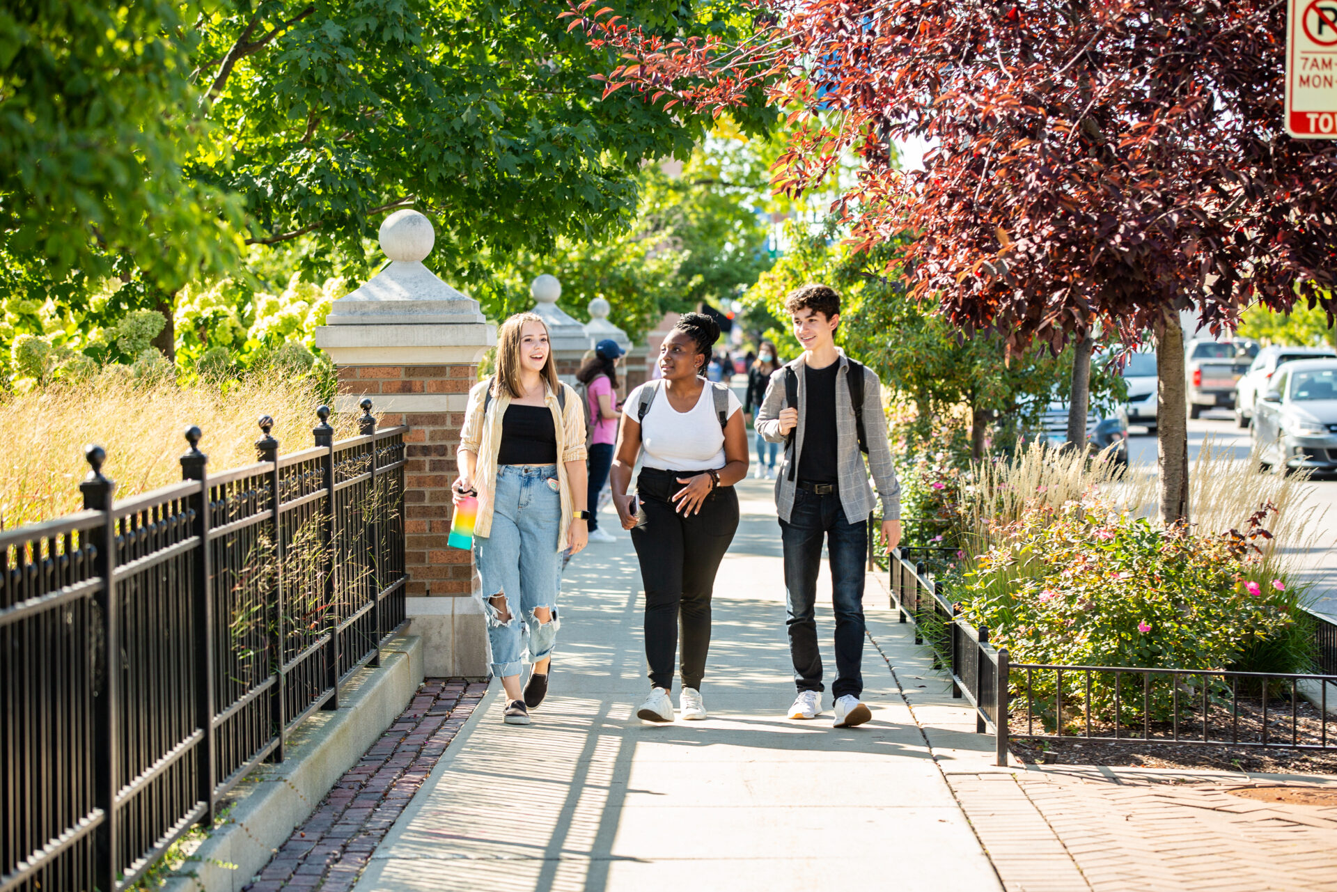 three students wearing backpacks walking down foster ave in front of North Park University