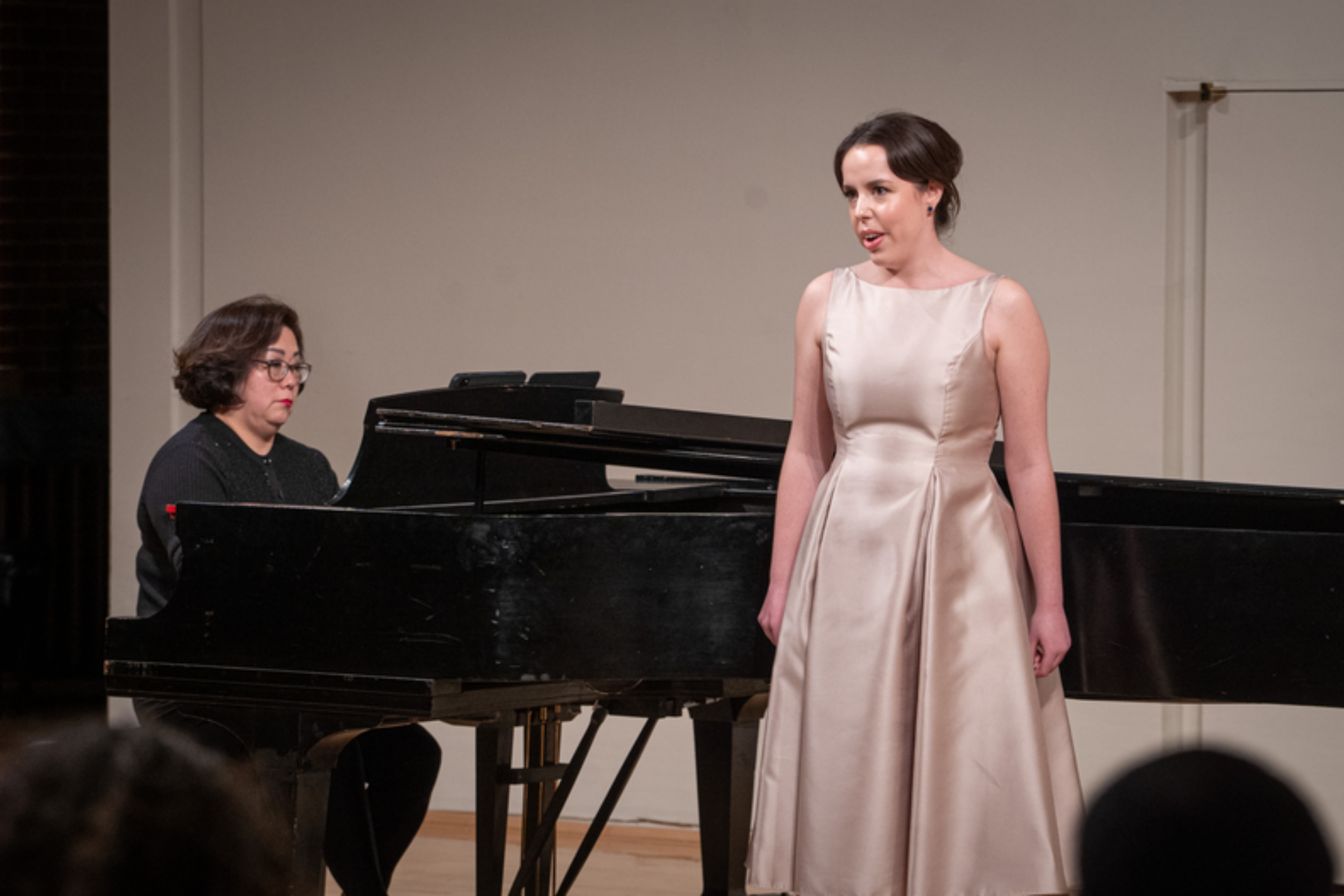 Graduate student singing at a performance while a piano is being played.
